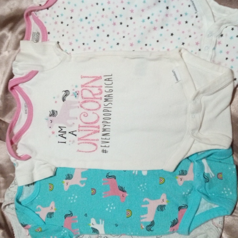 Set of 4 onesies size 3 to 6 months featuring unicorns, stars, and sheep.